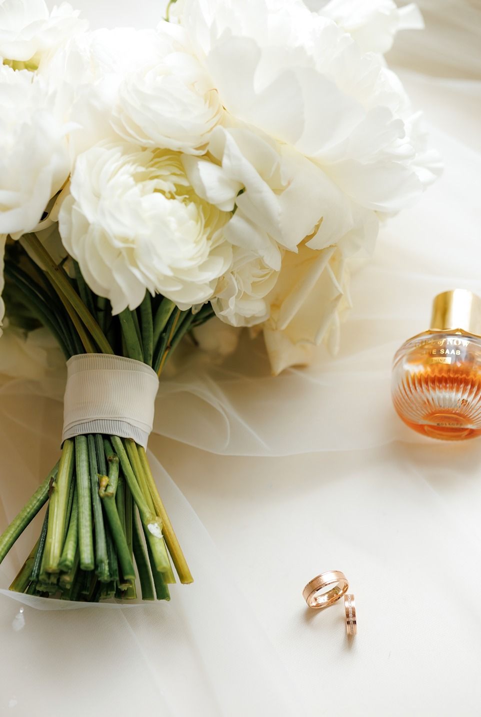 Bukiet weselny z białych kwiatów z obrączkami na białym obrusie